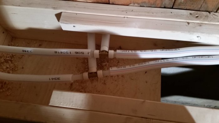 Installationsvy av vit rörsystem mellan träbalkar med Q&E kopplingar och expanderad slang för byggprojekt.