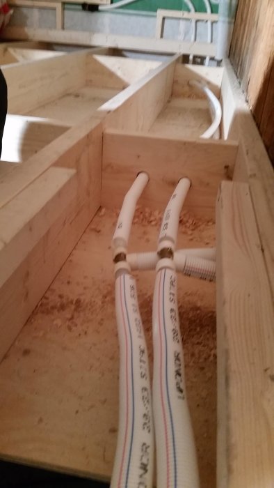 Flexibla rör kopplade med Q&E-teknik genom träbjälklag vid ett byggprojekt.