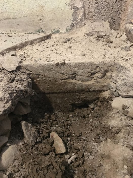 Provgrävning i golv visar tunn grund med ca 20 cm grundsula och begränsat utrymme för isolering.