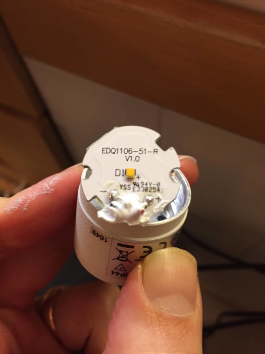 Isärskruvat ledchip i handen, med synliga lodningar och kretsuppgifter på baksidan, mot en suddig bakgrund.