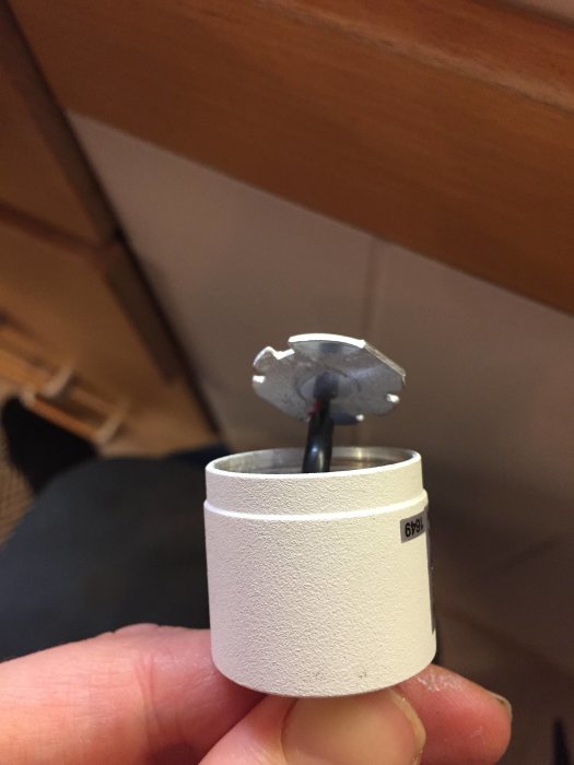 Hand håller en isärtagen LED-lampa som visar ett enkelt LED-chip monterat i änden av en kabel.