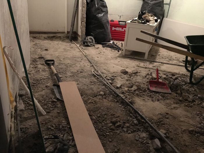 Renoveringsarbete med uppbilad betong och verktyg på ett golv under ombyggnation.