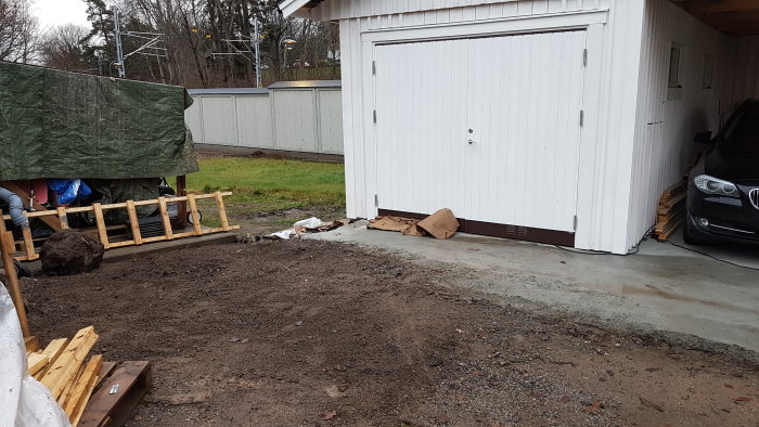 Nyligen urgrävd jordhög vid ett garage med monterade lås och trycken på dörr och port.