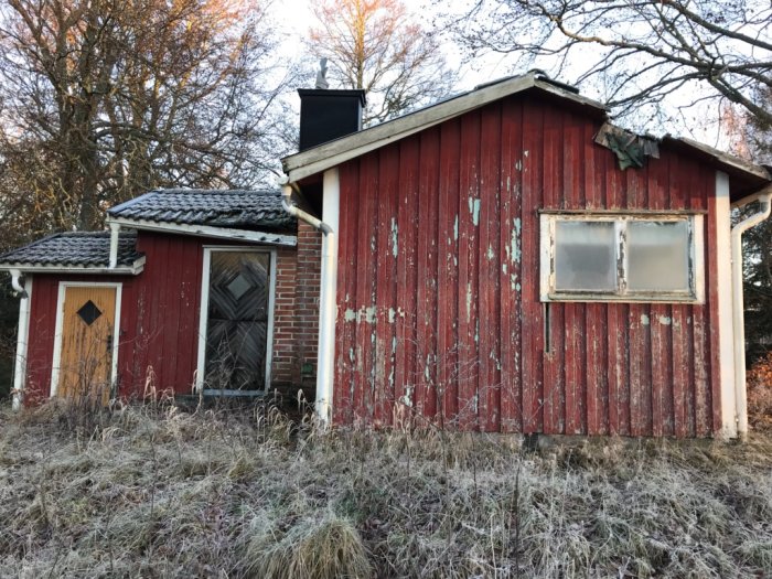 Gammalt obebott hus med rötmålad träfasad och slitet tak, tecken på förfall och övergivenhet.