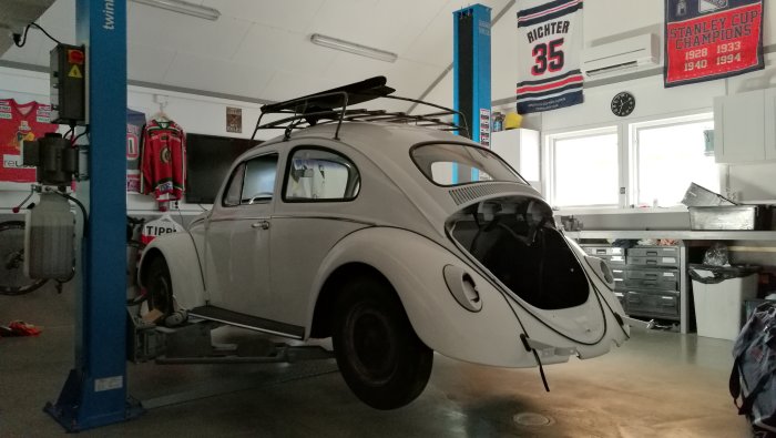 En klassisk bil av märket Volkswagen Typ 1, även känd som Bubbla, på en lyft i ett välorganiserat garage.