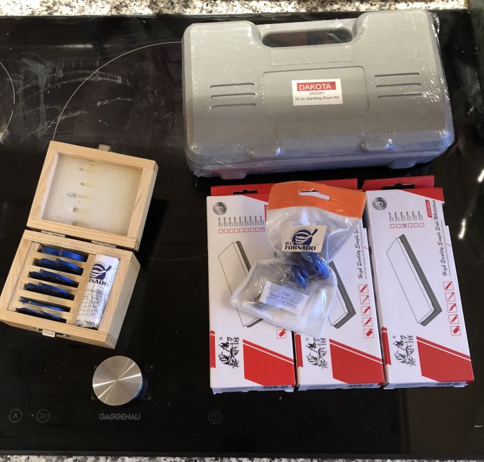 Verktyg och tillbehör för träbearbetning på ett köksbord, däribland en Dakota sliptrummesats och fräskit.