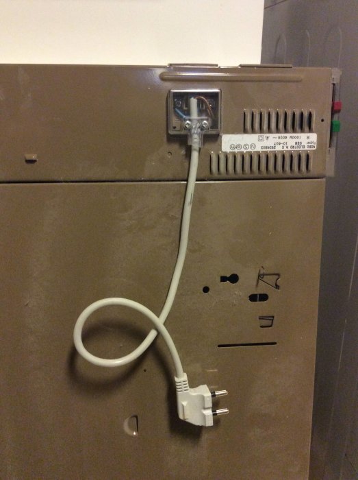 Gammal radiator med elkabel och stickkontakt, etikett visar tekniska specifikationer.