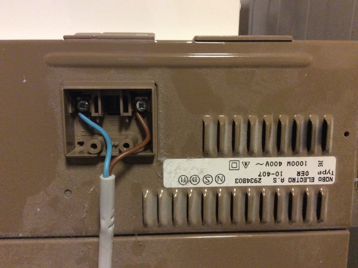 Gammal radiator med öppet elanslutningsområde och synliga kablar och etikett.