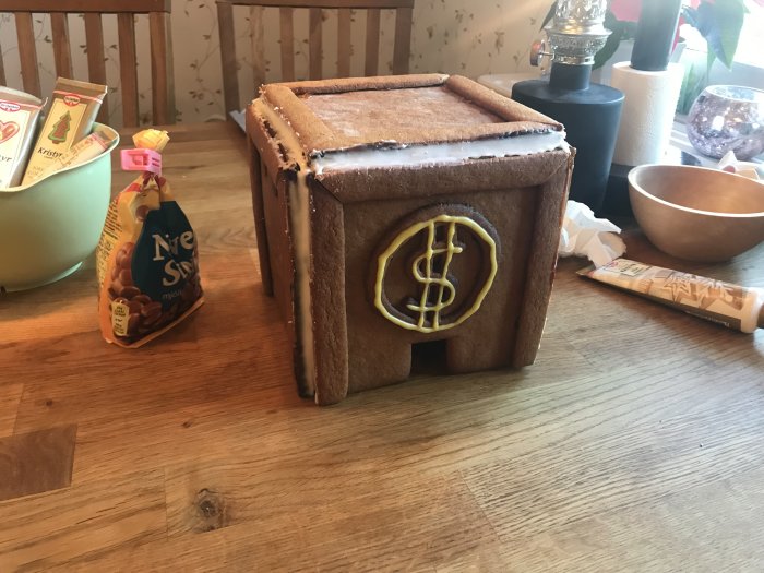 Hemmagjord pepparkakshusmodell av Von Ankas pengabinge med dollar-tecken, på ett köksbord.