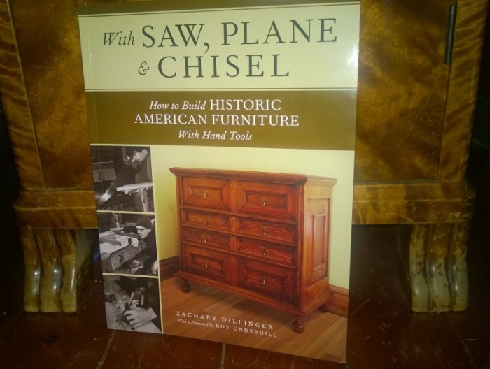 Bok om att bygga historiska amerikanska möbler med handverktyg på ett trägolv, nära en möbelfot.
