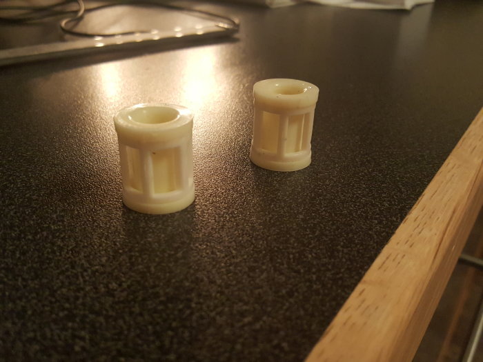 Två oanvända vita plastexcenterkopplingar för blandare på en köksbänk.