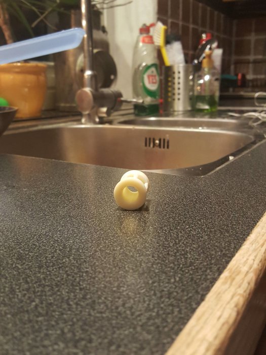 Ihålig föremål på köksbänk med diskho och rengöringsmedel i bakgrunden.