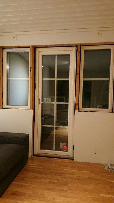 Nyinstallerade fönster och en helglasad balkongdörr i ett inomhus bostadsrum.