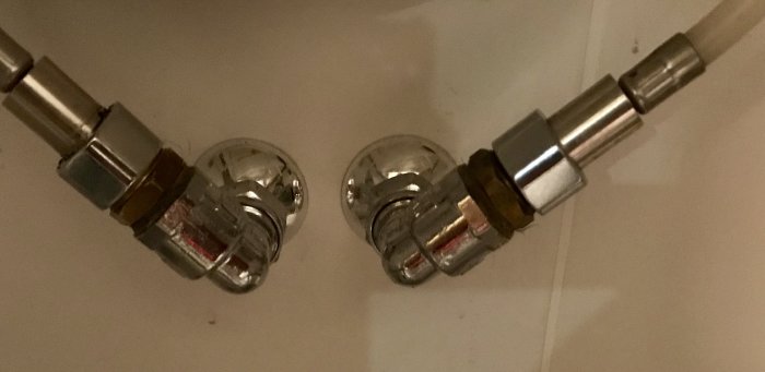 Metallkopplingar och vattenledningsslangar under diskbänk som verkar för korta för anslutning.