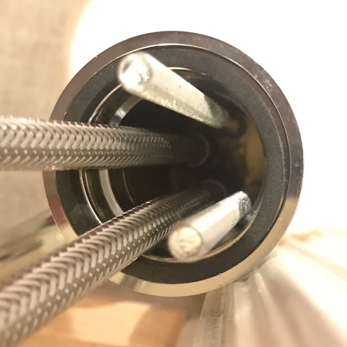 Närbild på anslutningarna under en ny tvättställsblandare med synliga 3/8” kopplingar.