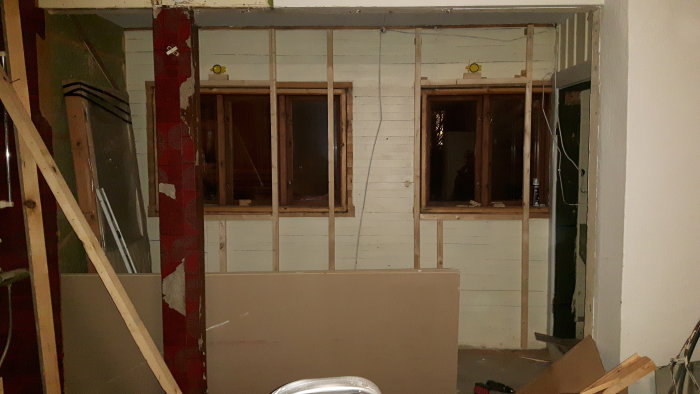 Renoveringsprojekt med nyreglad vägg, isoleringsarbete påbörjat, utsatta platser för PVC-fönster och synlig skarv på balk i taket.