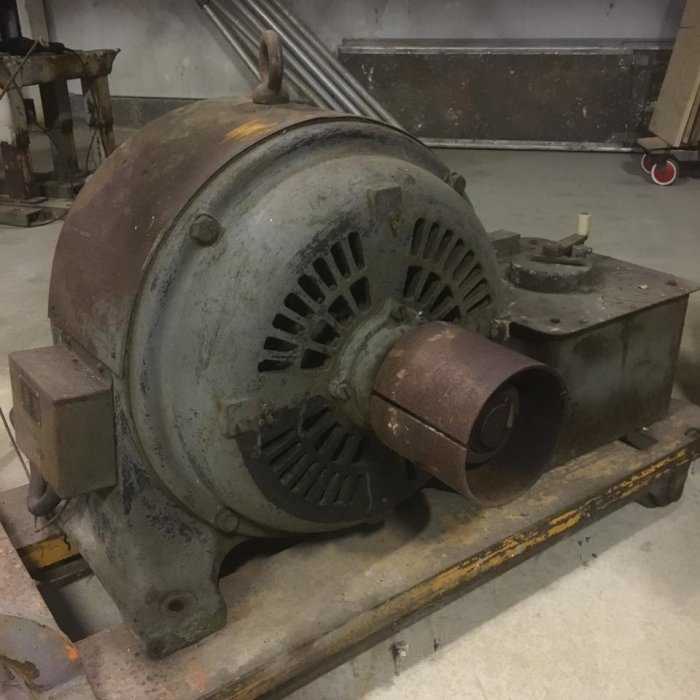 Gammal stor elektromotor på 300kg från Capo i Arlöv, placerad på ett trägolv.