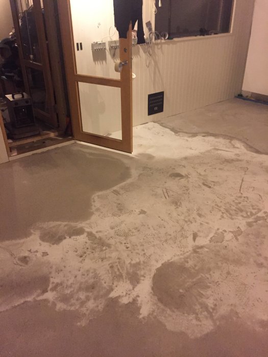 Poröst, ojämnt flytspacklat golv med vit hinna i bergrum, visande resultat efter tillsats av för mycket vatten.