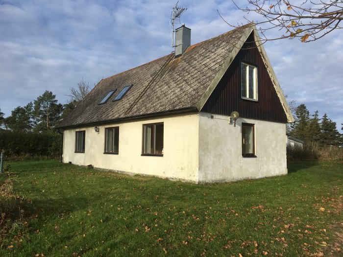 Ett litet gammalt hus på landet med "potential", ojämn puts och slitet tak, omringat av grönska.