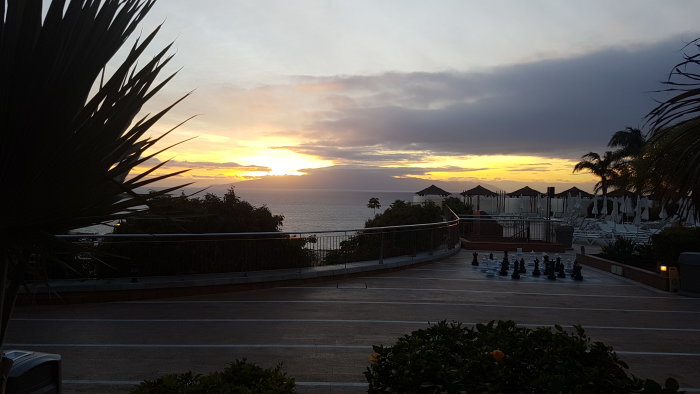 Vy över La Gomera i solnedgången, sedd från en terrass på Teneriffa med stängda parasoller.