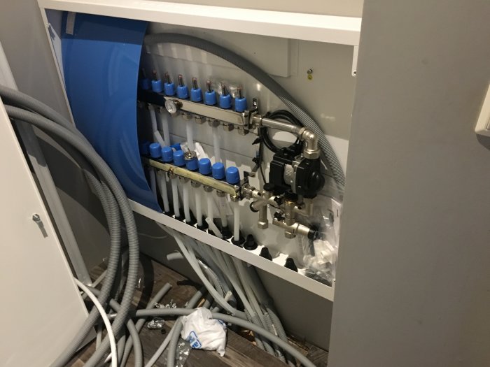 Rörinstallationer och kopplingar under pågående badrumsrenovering med synliga slangar och acc-tank.