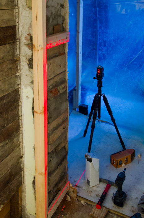En dörröppning som utvidgats, med laser för mätning och träreglar för stöd.