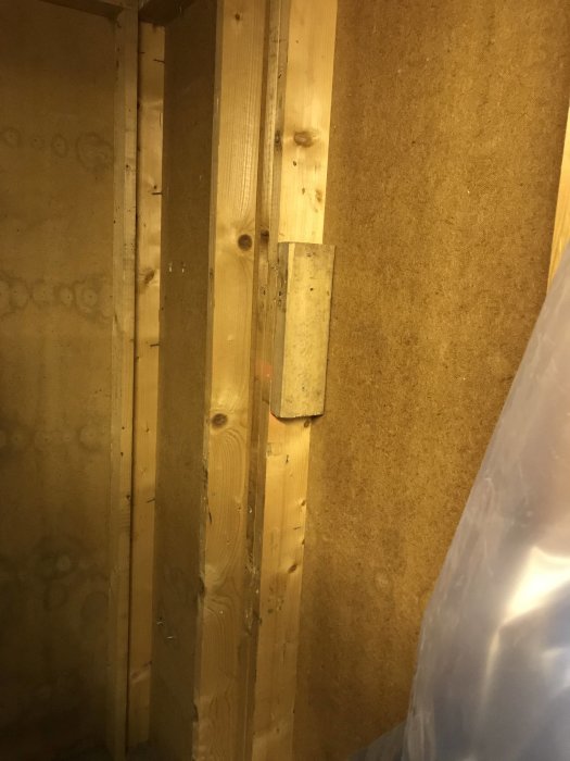 Innervägg i garage med synlig spånskiva och vertikala träreglar, föreslagen för isolering.