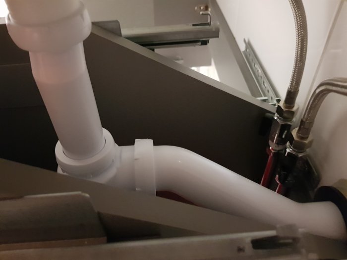 Nyinstallerat vattenlås och rör under handfat, indikerar problem med klunkande ljud vid avlopp.