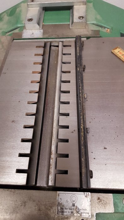 Detaljbild av en hyvelmaskins kutter med tre stålblad och fjädrar synliga på maskinens arbetsyta.