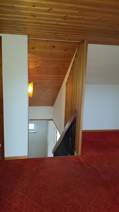Interiör av 1960-talshus före renovering med röd heltäckningsmatta och träpanel på väggar och tak.