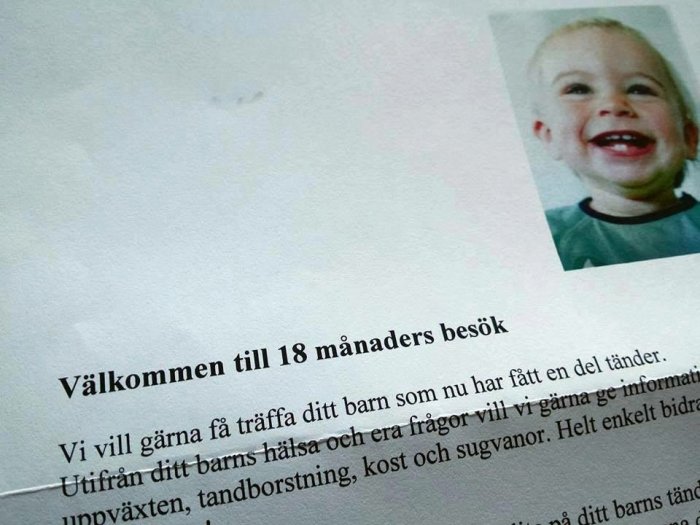 Leende liten pojke visas på en inbjudan till 18 månaders besök med text om tandhälsa.