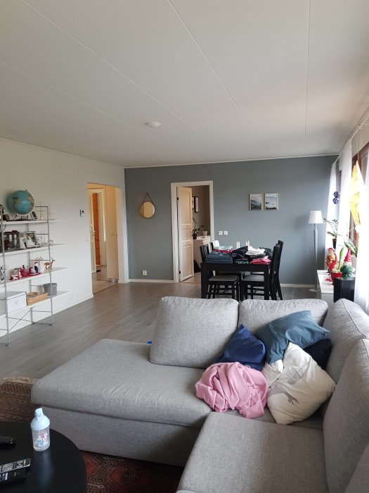 Efterbild av ett vardagsrum med soffa, matsalsbord och öppna dörrar till andra rum.
