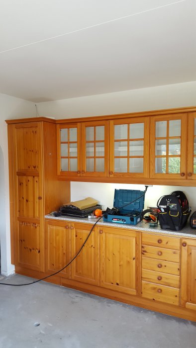 Ett kök med träköksskåp och verktyg på bänkskivan innan renovering.