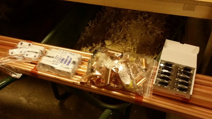 Kopparrör och VVS-delar utspridda på ett arbetsbord, redo för installation.