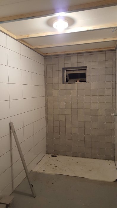 Renovering av badrum, halvt kaklade väggar och osätt golv före slutlig installation.
