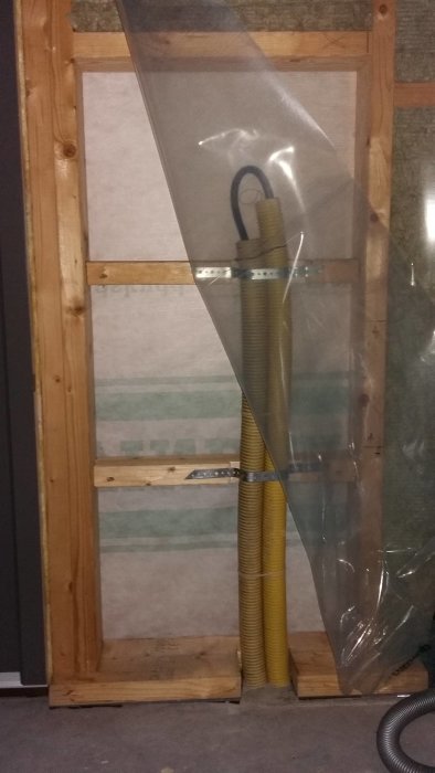 Flexibla ventilationsrör placerade inne i en oavslutad väggkonstruktion med isolering synlig.