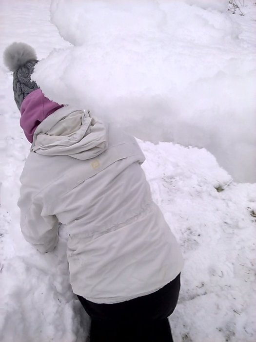 Person använder kroppen för att kasta snö som en snöslunga, humoristisk referens till byggprojekt.