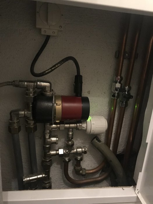 Värmesystem med rör och cirkulationspump i teknikskåp.
