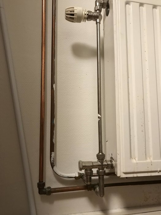 Rörinstallation med övergång från järnrör till 22 mm kopparledning vid en radiator.