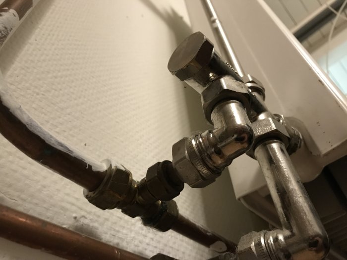 Radiatoranslutning med rörförbindelser och ventiler, inga synliga skruvar.