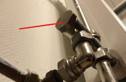 Rörkoppling nära en vit vägg, markerad med röd linje för att visa dimensionen "2 inches".