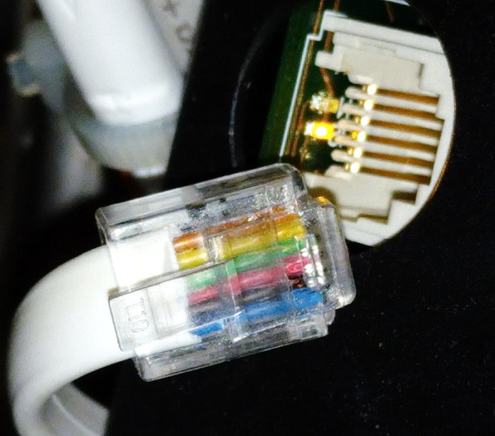 Närbild på en oskärmad RJ45-nätverkskontakt med färgkodade kablar anslutna.