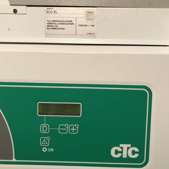 Kontrollpanel på en CTC ECO EL värmepump med felmeddelandet KOMPR FASFÖLJDFE LARM RESET och en blinkande röd varningstriangel.