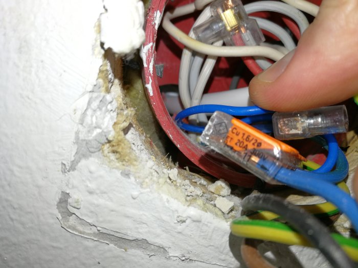 Elektrisk dosa med hål i baksidan och lösa kablar med synlig isolering.