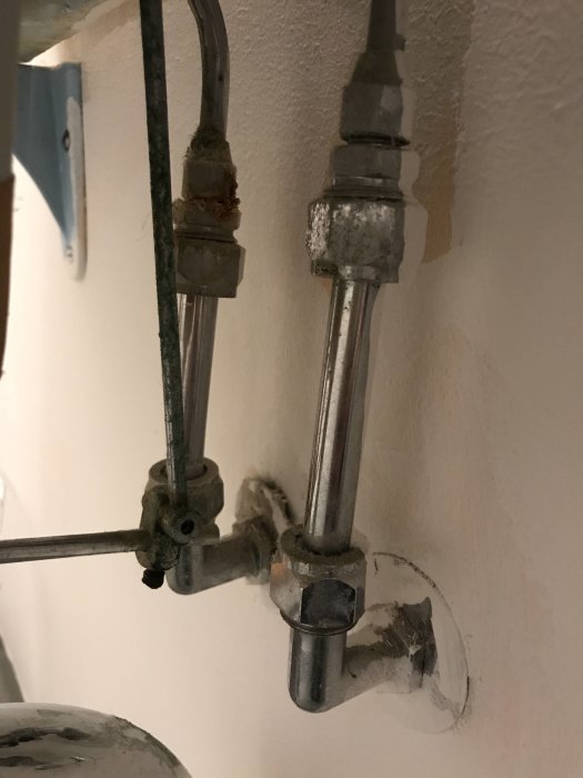 Gammal blandare med vinklade vägganslutningar och kopparrör som ska uppgraderas.