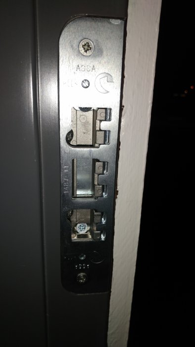 Närbild av ett nytt justerbart låsbleck monterat på en dörrkarm med extra skruvar för att fixera.