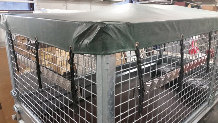 Durkplåt av aluminium monterad på en släpvagn med grönt skyddstak och näthinder.