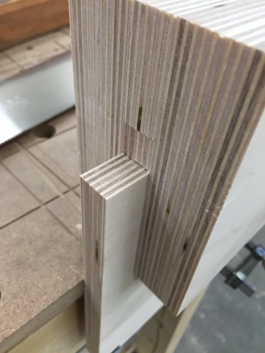 Ett stöd för japansåg infäst i ett laminat hyllplan, visande urtaget för precisionssågning.