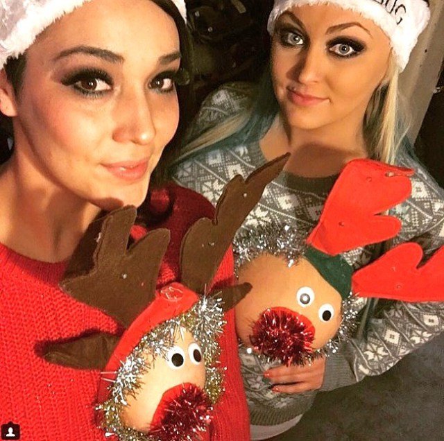 Två kvinnor med jultomtemössor som poserar i jultröjor med renmotiv.