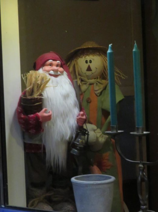 Figurer som föreställer en tomte och en sommarfigur bredvid stearinljus, dekorerat för jul.